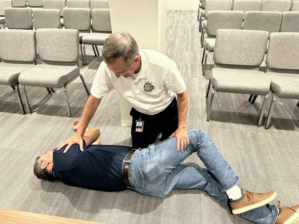 A responder turns an unconscious breathing patient on their side after looking for breathing.