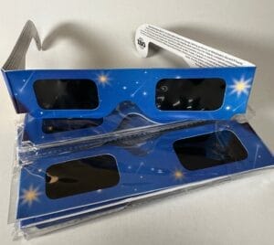 Several pairs of colorful solar eclipse glasses on a white background.